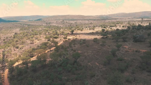 Shadow lying over african savannah woodland landscape with dirt road. photo