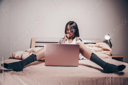 a young Asian webcam model girl is sitting in front of a laptop. she communicates and shows her charms. low depth of focus,selective focus