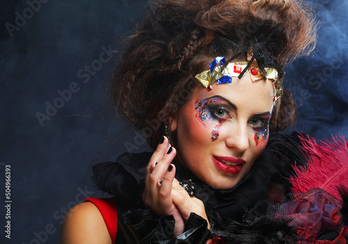 Young woman with creative makeup and and hairdo posing on dark background. Party time and halloween. photo