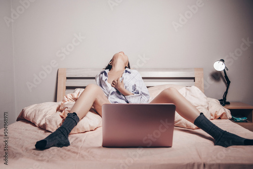a young Asian webcam model girl is sitting in front of a laptop with her legs spread. she communicates and shows her charms. low depth of focus,artistic photo processing