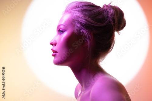 Beauty portrait of young woman in profile in neon light. Concept fashionable portrait