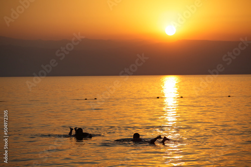 People floating in the dead sea at sunset, Jordan © Massimo Pizzotti