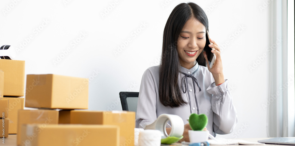 Asian businesswoman is taking online orders from a phone and chatting with customers to confirm their order, Selling products online or doing freelance work at home concept. Asian businesswoman is taking online orders from a phone and chatting with customers to confirm their order, Selling products online or doing freelance work at home concept.