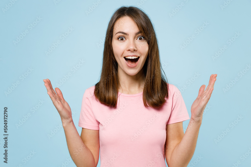 Young excited fun cool shocked amazed impressed happy woman 20s wearing pink t-shirt look camera spread hands isolated on pastel plain light blue background studio portrait. People lifestyle concept. Young excited fun cool shocked amazed impressed happy woman 20s wearing pink t-shirt look camera spread hands isolated on pastel plain light blue background studio portrait. People lifestyle concept.