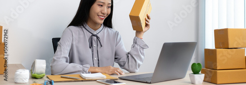 Young Asian woman chatting with a customer on a laptop and displays the product before delivery to confirm the order, Selling products online or doing freelance work at home concept. photo