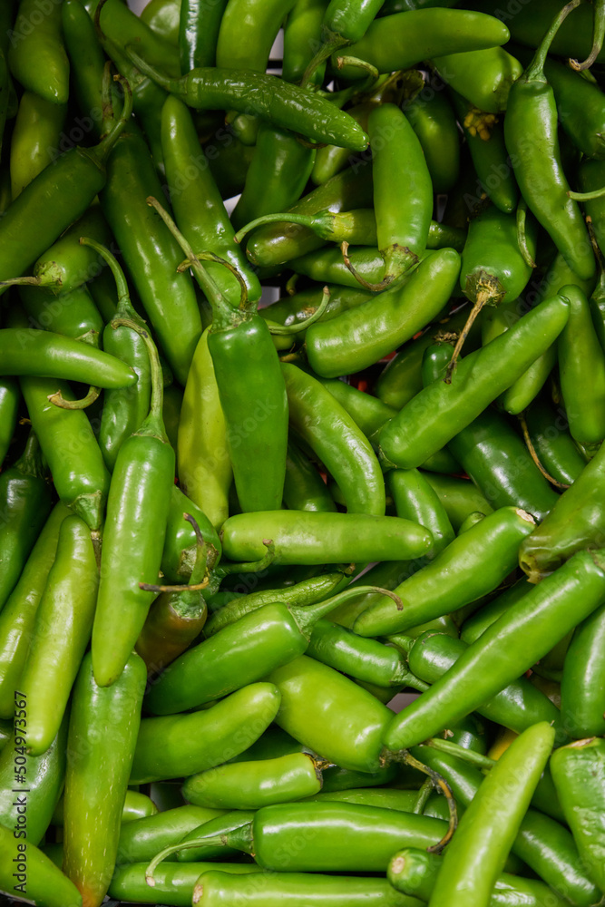 Green chilies placed on a shelf for sale within a market