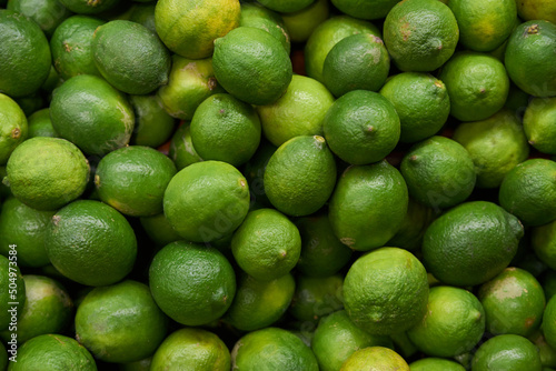 Fototapeta Naklejka Na Ścianę i Meble -  Green lemons placed on a shelf for sale at a market
