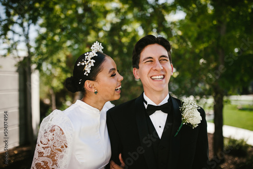Latina bride and multiracial groom laugh and smile after wedding