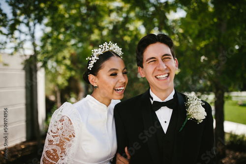 Multiracial groom and bride laughing after wedding ceremony photo