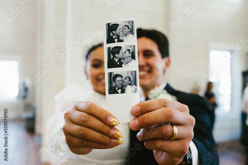 Bride and groom smile holding polaroid photograph of them