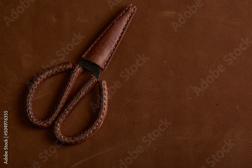 Old scissors in a vintage leather case on a natural leather background.