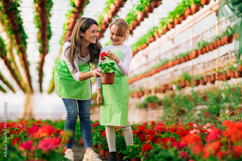 A young woman teaches her daughter about their small business in a flower greenhouse. A young woman teaches her daughter about their small business in a flower greenhouse.