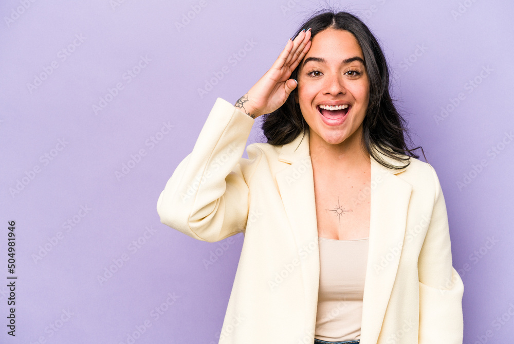 Young hispanic woman isolated on purple background shouts loud, keeps eyes opened and hands tense. Young hispanic woman isolated on purple background shouts loud, keeps eyes opened and hands tense.