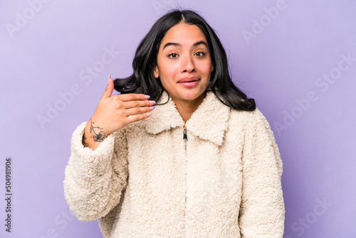 Young hispanic woman isolated on purple background laughing about something, covering mouth with hands. © Asier