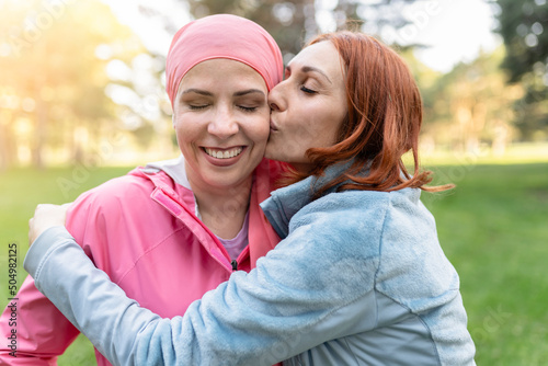 women hugging with closed eyes while kissing the fighter against cancer - concept fight against breast cancer -