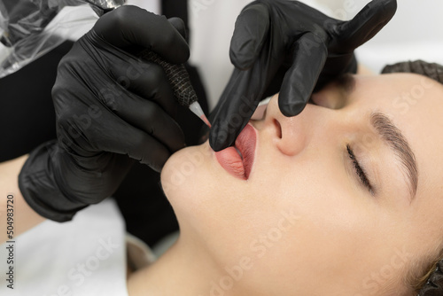 Close-up of the permanent makeup procedure. Lip makeup in the cosmetologist's salon.