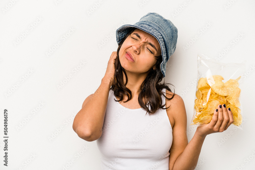 Young hispanic woman holding a bag of chips isolated on white background touching back of head, thinking and making a choice. Young hispanic woman holding a bag of chips isolated on white background touching back of head, thinking and making a choice.