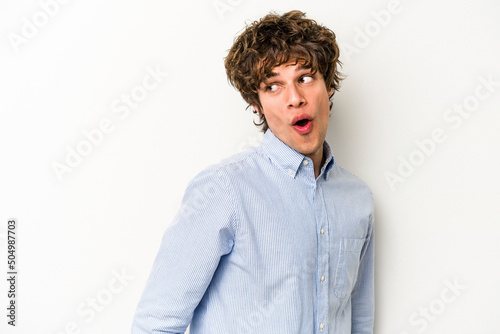 Young caucasian man isolated on white background looks aside smiling, cheerful and pleasant. © Asier