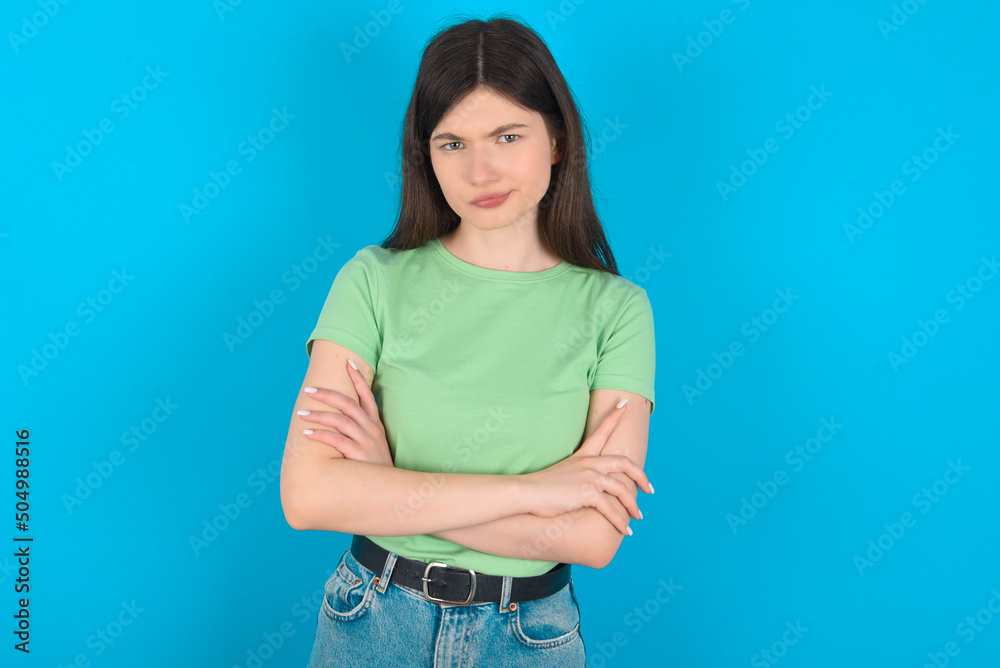 young beautiful Caucasian woman wearing green T-shirt over blue wall Pointing down with fingers showing advertisement, surprised face and open mouth