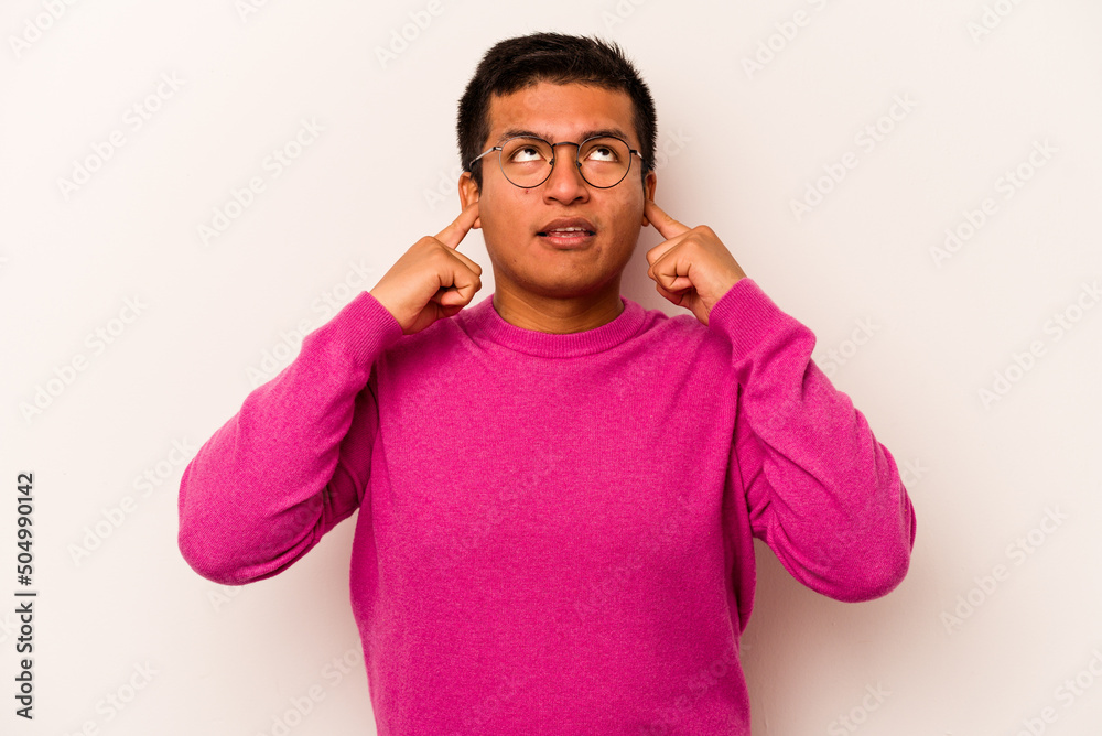 Young hispanic man isolated on white background covering ears with fingers, stressed and desperate by a loudly ambient. Young hispanic man isolated on white background covering ears with fingers, stressed and desperate by a loudly ambient.