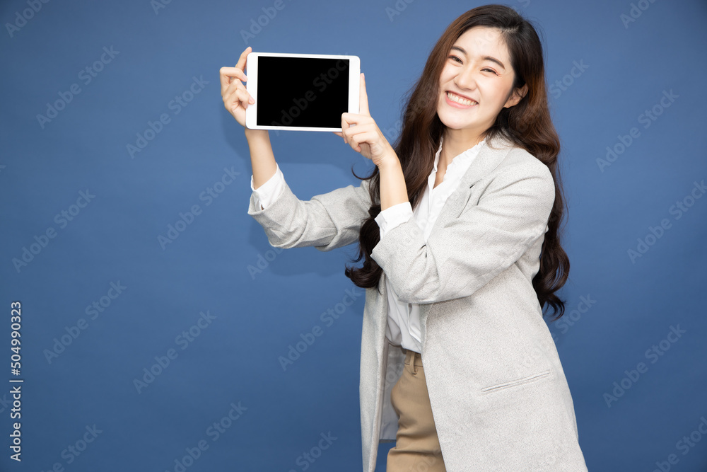 Young Asian businesswoman showing tablet on hand isolated on blue background