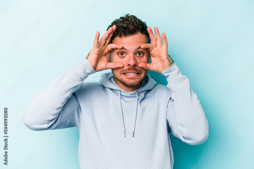 Young caucasian man isolated on blue background keeping eyes opened to find a success opportunity. Young caucasian man isolated on blue background keeping eyes opened to find a success opportunity.