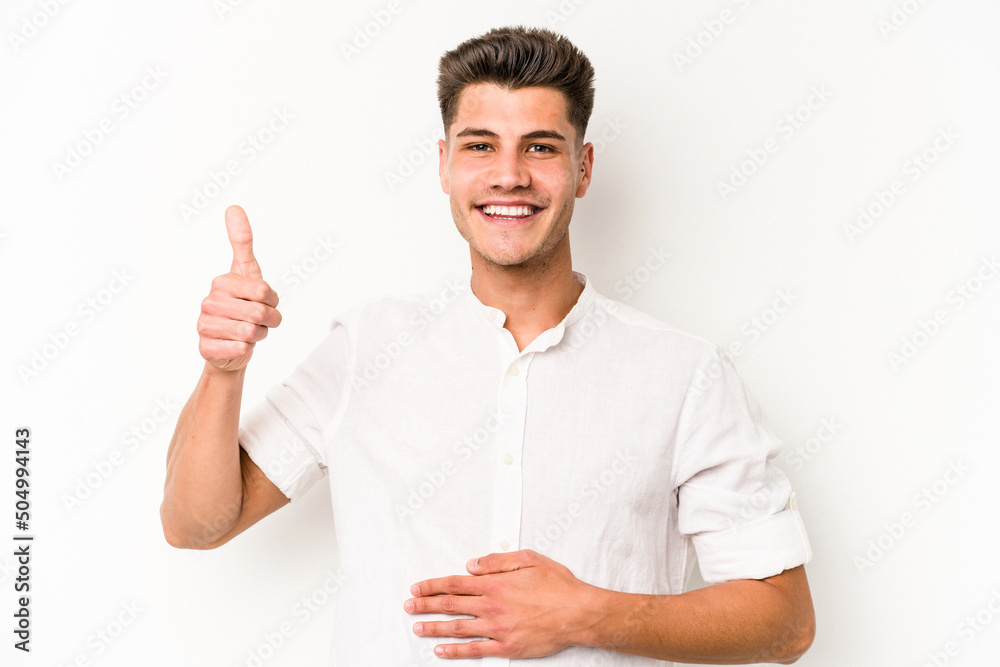 Young caucasian man isolated on white background touches tummy, smiles gently, eating and satisfaction concept. Young caucasian man isolated on white background touches tummy, smiles gently, eating and satisfaction concept.