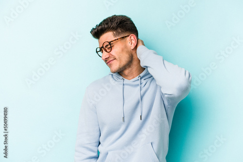Young caucasian man isolated on blue background suffering neck pain due to sedentary lifestyle. © Asier