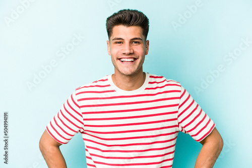 Wallpaper Mural Young caucasian man isolated on blue background confident keeping hands on hips. Torontodigital.ca