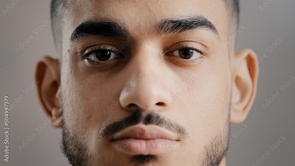 Obraz premium Close-up portrait of hispanic indian male serious young student man freelancer model stand indoor posing at camera with confident deep look millennial ethnic handsome brunet guy show facial expression