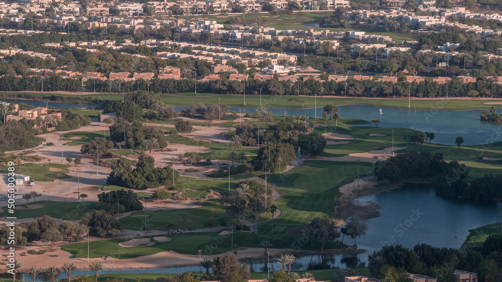 Aerial view to Golf course with green lawn and lakes, villa houses behind it timelapse.
