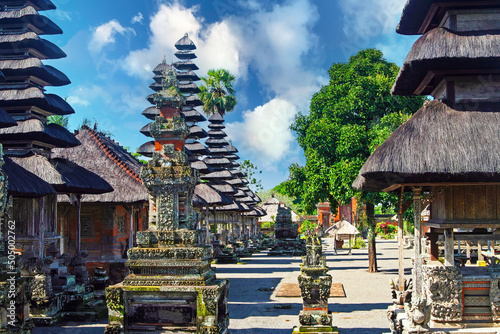 Pura Taman Ayun Temple, Bali - Beautiful holy Hindu temple square with traditional meru towers, multiple thatched roofs , blue summer sky, green trees photo