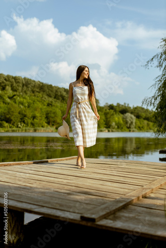 Young woman walking on the wooden pier at the calm lake