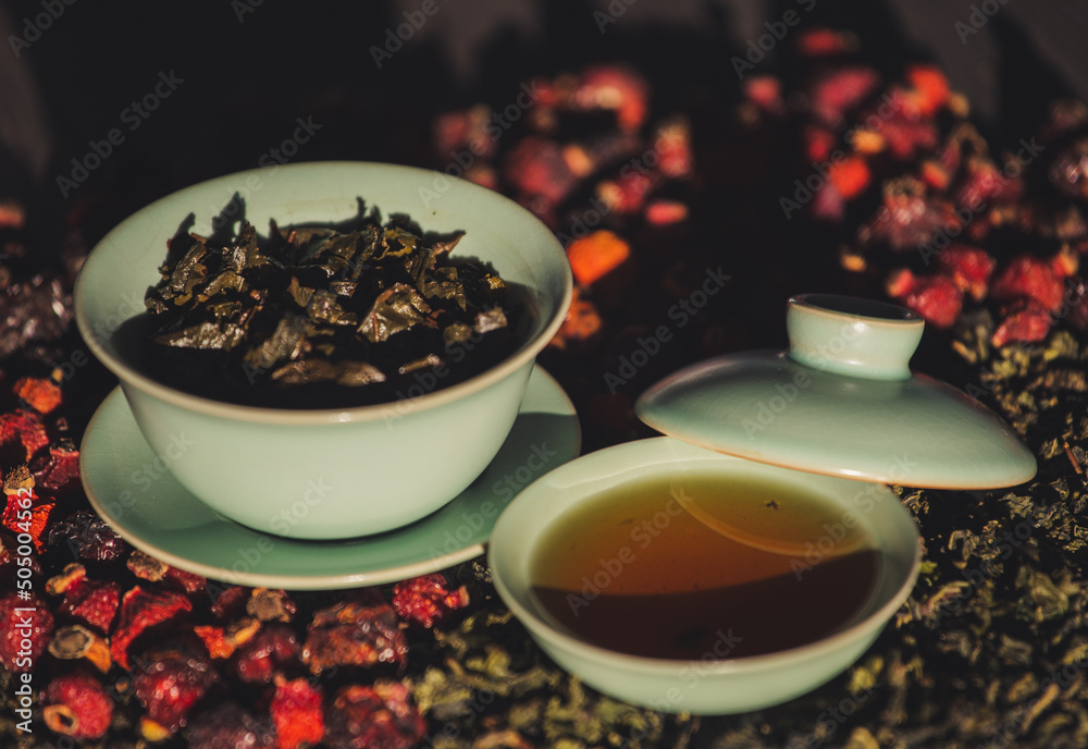Gaivan and bowls with green tea and tea leaves on a brown background close-up, selective focus. Tea ceremony. Traditional Chinese tea ware. Gaiwan cup. Zhu yao ceramic. Chinese ceramics. Relax. Gaivan and bowls with green tea and tea leaves on a brown background close-up, selective focus. Tea ceremony. Traditional Chinese tea ware. Gaiwan cup. Zhu yao ceramic. Chinese ceramics. Relax.