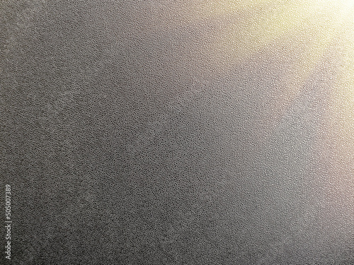 Photo of the texture of black plastic with the rays of the sun.Plastic background for text.Grey background made of plastic panel.