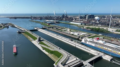 4k aerial video of cruise ship leaving large sea sluice towards Amsterdam in the Netherlands. Tata steel factory in the back ground photo