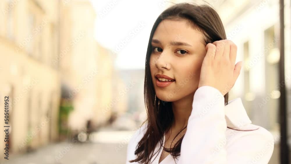 Portrait of attractive dark haired woman while standing in the city street. Beautiful woman looking at the camera outside. Portrait of attractive dark haired woman while standing in the city street. Beautiful woman looking at the camera outside.