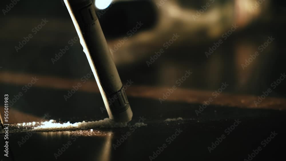  Cocaine or heroin addict sniffing a row of cocaine crushed pills with a twisted dollar bill, closeup. The concept of drug addiction and social degradation
