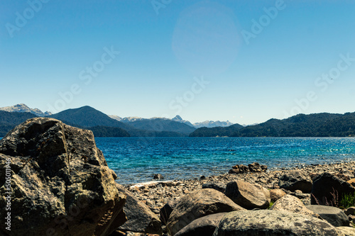 Beautiful view from the coast with huge stones, colorful lake and ridge mountains in the background. Lake Nahuel Huapi. Villa La Angostura, Argentina