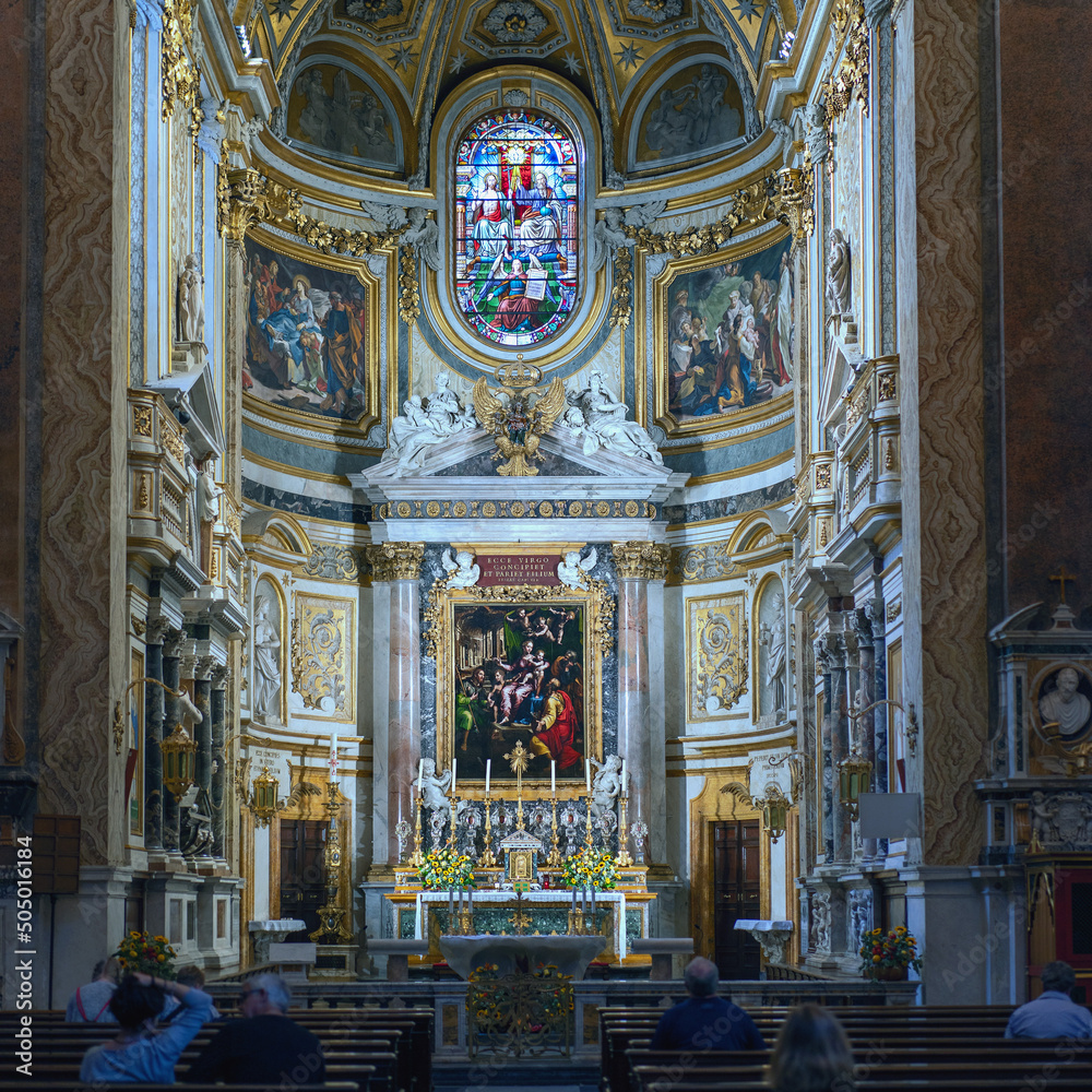 The interior of the Catholic Cathedral in Rome with paintings on religious themes and praying parishioners