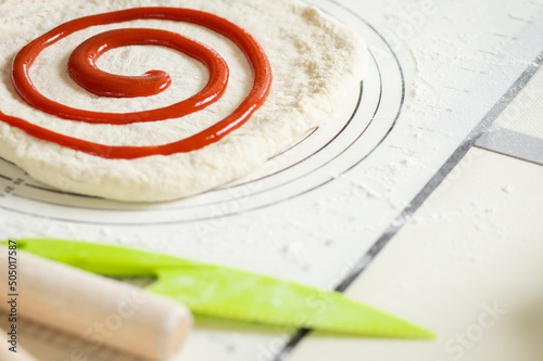 Berry jam spirally applied to rolled out dough for a sweet dessert roll. photo