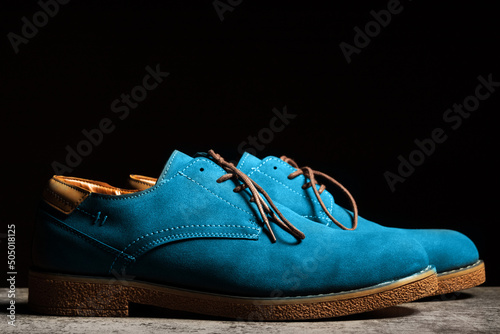 Side view of blue concert shoes with laces on a black background. © Roman