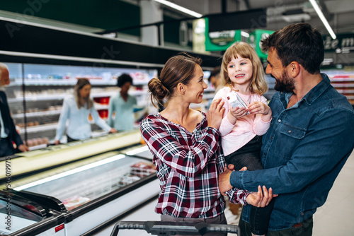 Happy young family buying groceries together at the supermarket.