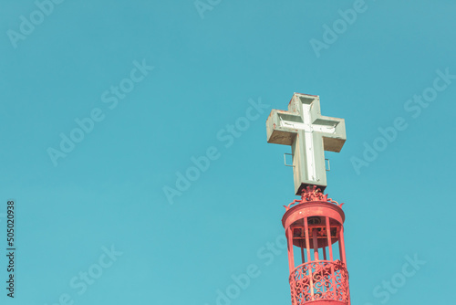 cross on the top of a metal structure with a blue sky