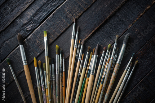 Group of old used paintbrushes on dark wooden background,Flat lay.