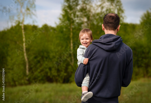 Young father in nature holding small daughter in the arms. Copy space.