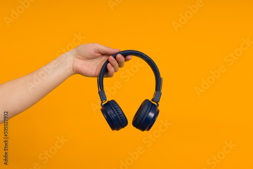 female hand holds modern headphones on a colored background