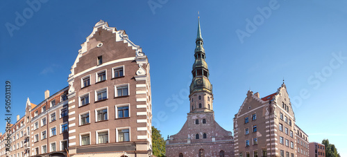 St Peter's Church in Riga, Latvia. Panoramic banner image with St Peters Church and historic buildings of Old Riga on a bright sunny day with blue sky. photo