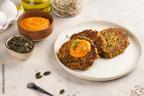 Vegetable carrot and quinoa pancakes on a plate topped with paprika hummus, sunflower seeds. Healthy vegetarian food - plant based diet concept.