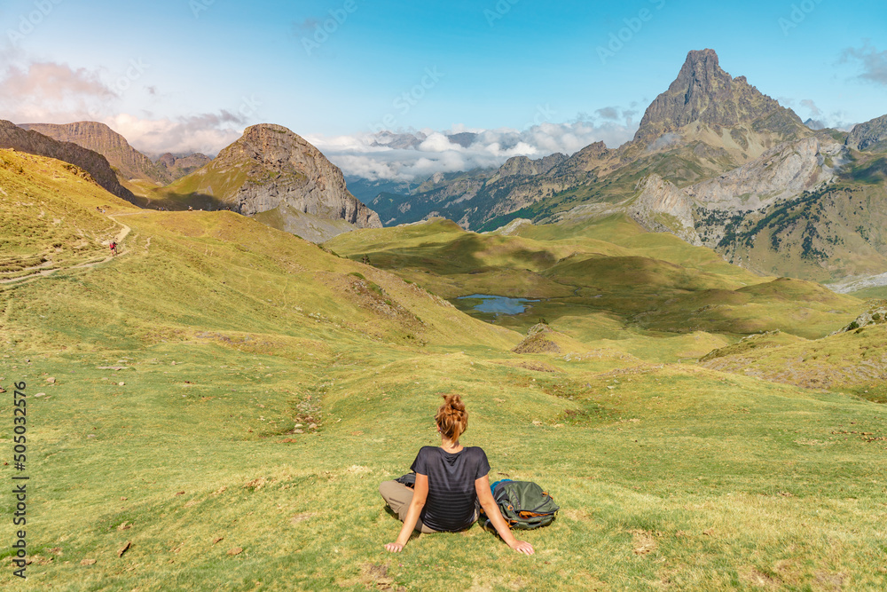 Young Attractive Woman sitting resting in a Beautiful wild mountain Landscape in summer. Discovery Travel Destination Concept.